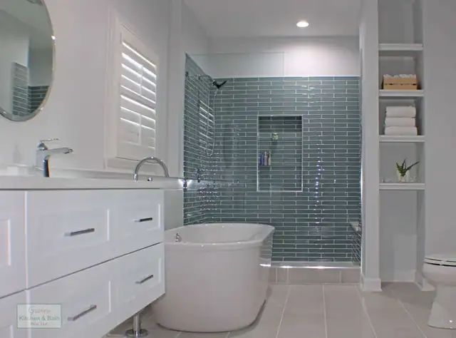 Spa-style bathroom in Springfield, TN with a freestanding tub, blue-green glass subway tile shower and built-in linen shelves