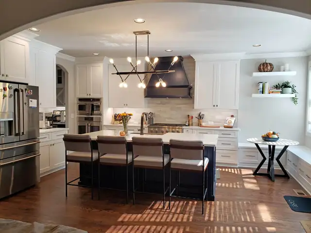 Kitchen with white cabinets, a navy island and matching navy range hood, modern chandelier and hardwood floors