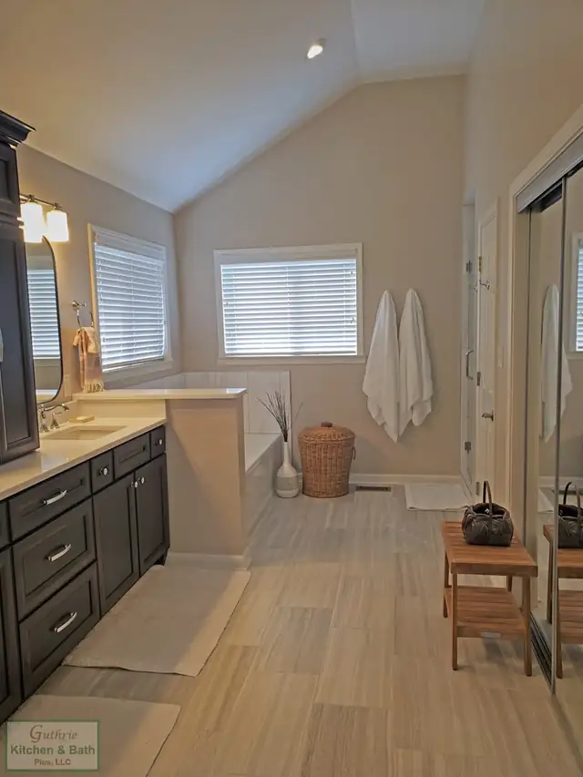 Bathroom with a dark wood vanity, vaulted ceiling and soaking tub under a window