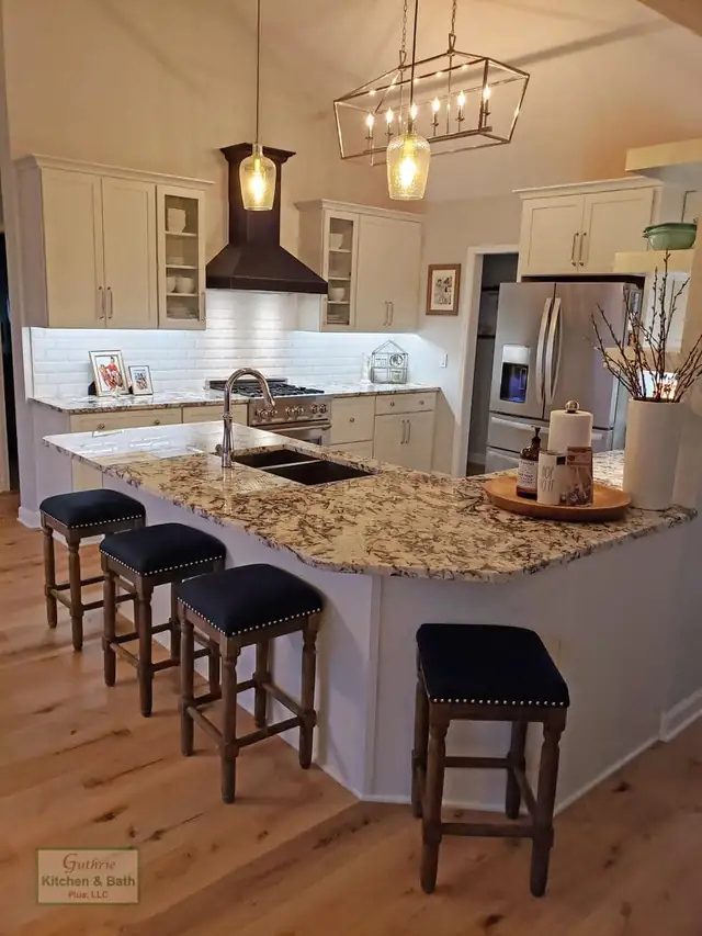 Clarksville, TN kitchen with a granite-topped island, white cabinets, black range hood and lantern pendants